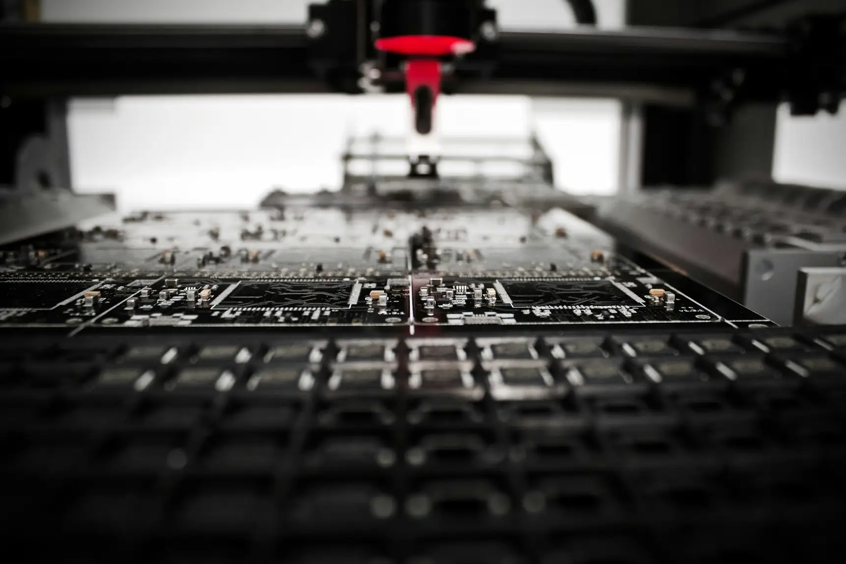 A pick-and-place machine setting surface-mount components onto a panel of circuit boards, component tape reels feeding in below